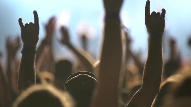 A huge crowd at a rock concert. Fans waving their hands. Slow Motion.