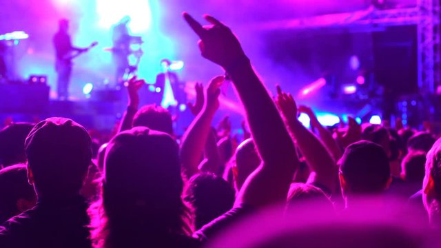 A huge crowd at a rock concert. Fans waving their hands.
