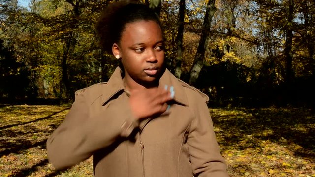 Young beautiful african happy girl stand in woods and adjusts her appearance