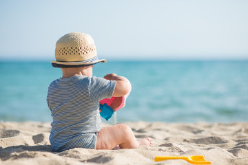 Cute baby boy playing with beach toys on tropical beach