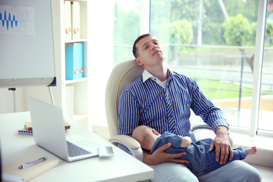 Sleeping Man Holding Sleeping Baby  In Office