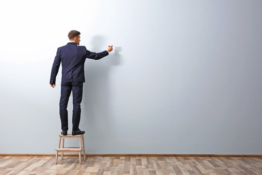 Man Writing Something On Grey Wall