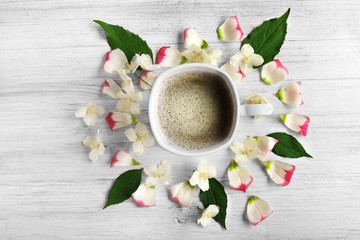 Cup of coffee with fresh flowers lying around on wooden background