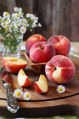 Fresh peaches and bouquet of daisies © photosimysia