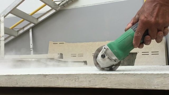 slow motion industrial workers working with electric grinder cutting concrete at construction site.