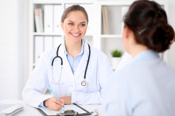 Fototapeta premium Friendly smiling doctor and patient sitting at the table. Very good news and high level medical service concept.