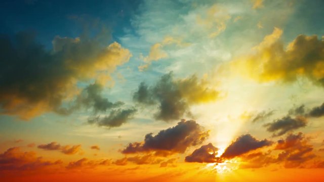 Tropical Sunset in Timelapse, with playful, puffy clouds drifting and building in bold colors of blue, orange, yellow and red. Video 4k