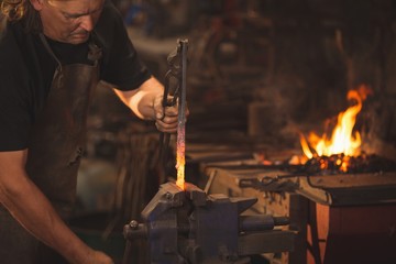 Blacksmith working on a heated iron rod in workshop