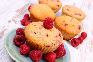 Fresh baked muffins with raspberries on old wooden background, delicious dessert