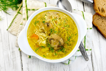 Soup with champignons and noodles in bowl on board top