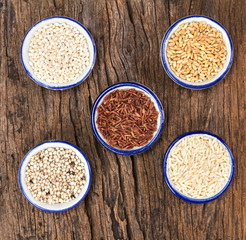 Variety of grain rice in cup on natural wooden background 