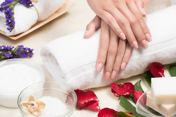 Obraz na płótnie Canvas beauty woman hands with a bowl of aroma spa water on a table,close-up,Spa setting with rose pink flowers and petals,bath salt and body-oil