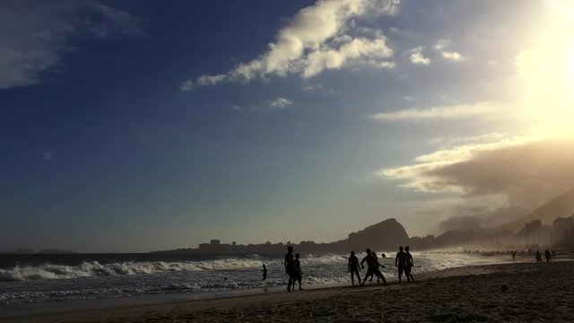 Timelapse of sunset on Copacabana Beach with altinho beach football silhouettes playing in the waves on the shore in Rio de Janeiro, Brazil 