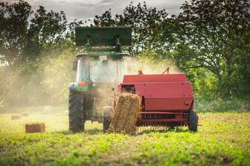 Baling tractor in the field at sunset © ValentinValkov
