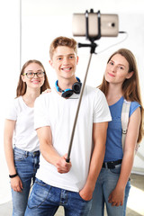 Obraz premium Selfie w szkole.Grupa przyjaciół robi zdjęcie selfie telefonem umieszczonym na monopodzie