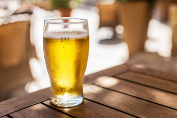 Glass of light beer on the wooden table.