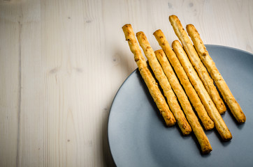 rustic breadsticks in a dish on wood table, close up, background