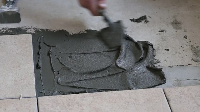 Floor construction with tiles top view. Professional worker finishing home room floor with tiles on floor
