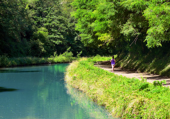 Fototapeta na wymiar Active woman runner jogging near canal river, outdoors running, sport and healthy lifestyle concept 