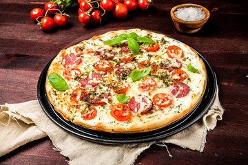 Obraz na płótnie Canvas Pizza mit Kräuterquark Tomaten und Salami
