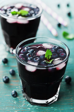 Blueberry lemonade or cocktail on teal rustic table, fresh summer berry juice
