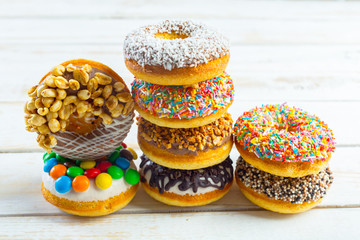 Collection of tasty donuts on white wooden board