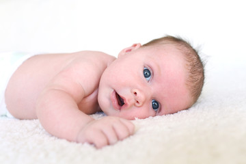 Cute blue-eyed 1 months baby girl lying on belly