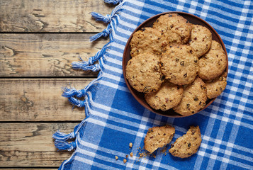 Traditional baked cereal oatmeal cookies with raisins and chocolate healthy sweet dessert snack food on clay dish on wooden table background.