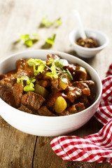 Goulash, served in white bowl with fresh herbs