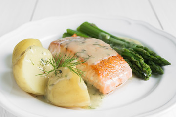 Grilled salmon with boiled potatoes and asparagus on white plate