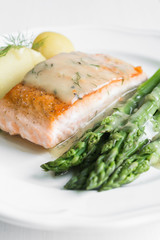 Grilled salmon with boiled potatoes and asparagus on white plate