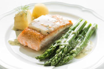 Grilled salmon with boiled potatoes and asparagus on white plate