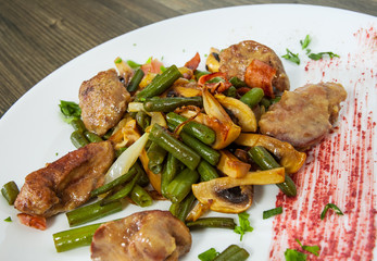 chicken liver with bacon, mushrooms and green beans on wooden table