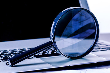 Closeup images of magnifying glass on laptop keyboard