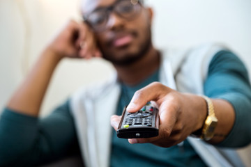 Handsome young black man watching tv at home.