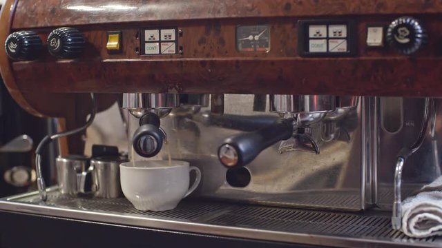 Close Up Of Coffee Machine In Use: Hot Coffee Pouring Into White Cup And Then Male Hand Pushing The Button To Stop It