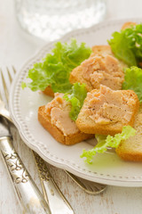 toasts with fish pate on white plate on white background