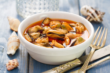 mussels with sauce in white dish on blue background