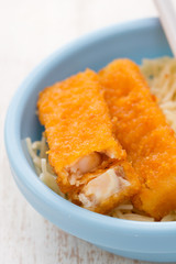 fish sticks with pasta in blue bowl on white wooden background