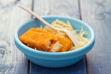 fish sticks with pasta in blue bowl on blue wooden background
