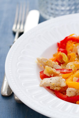 chicken with vegetables on white plate on blue wooden background