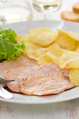 fried meat with potato chips and fresh lettuce on white dish on white background