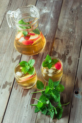 Two glass and carafe of green tea with mint and apples
