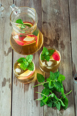 Two glass and carafe of green tea with mint and apples