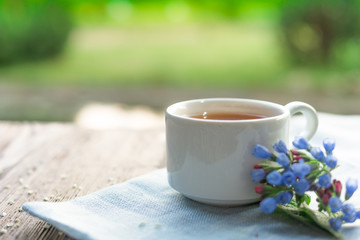 Сup with linden tea and flowers on wooden table in garden