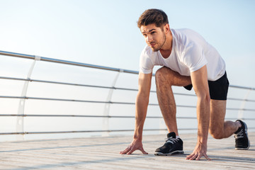 Concentrared young sportsman is ready to run outdoors