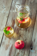 Glass and carafe of green tea with mint and apples