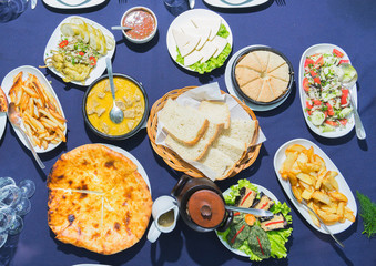 Overhead view on table with traditional georgian food: hachapuri, sacivi,  salad, cheese, chadi, eggplant, phali. Selective focus.