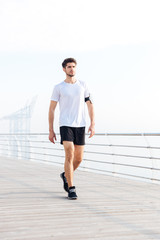 Attractive young sportsman walking on pier