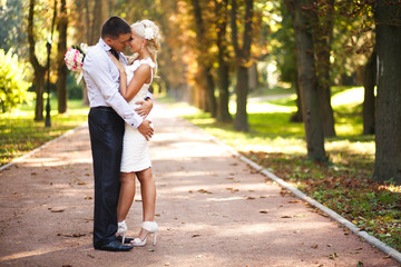 Fototapeta premium Groom fold a tender blonde bride in his arms